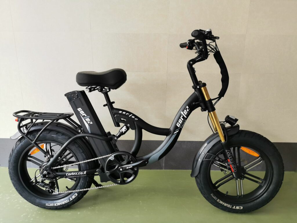 אופניים חשמליים מתקפלים בצבע שחור עם צמיגים רחבים, מותקנים עם סוללה וידית אחיזה.