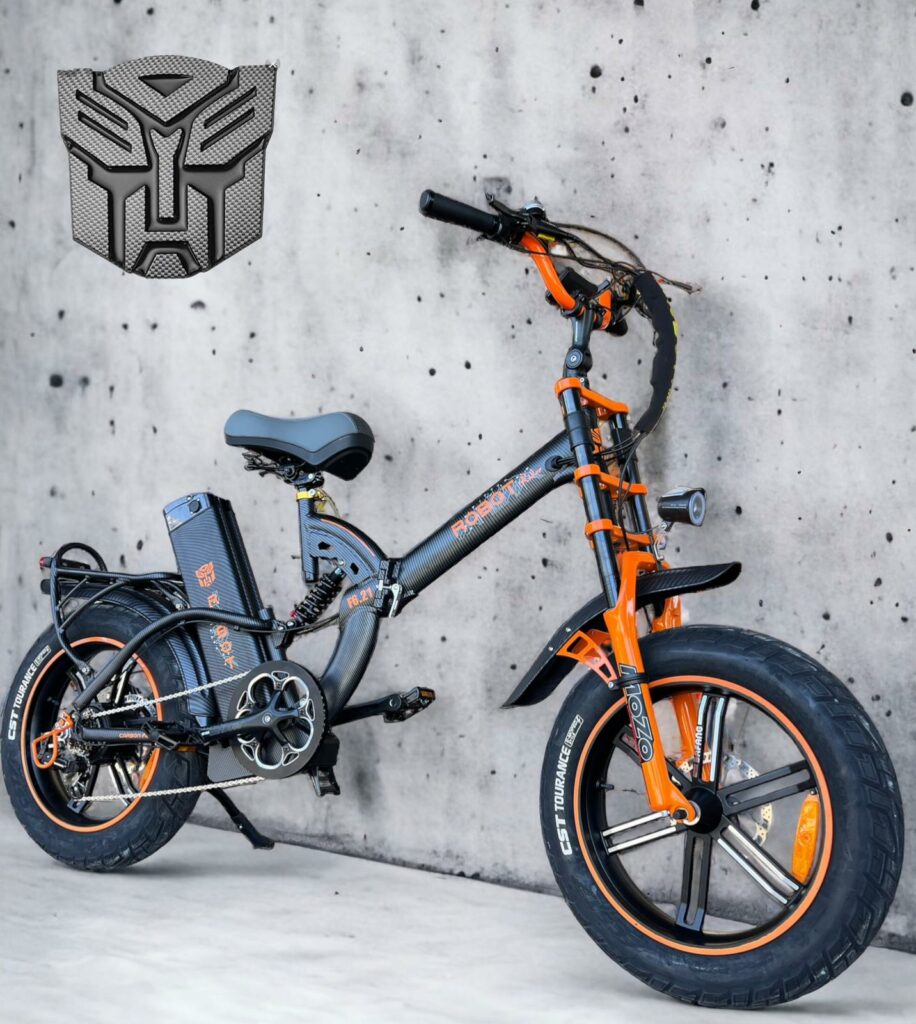 אופניים חשמליים מתקפלים בצבעים שחור וכתום, עם סוללה וגלגלים רחבים, על רקע קיר בטון.